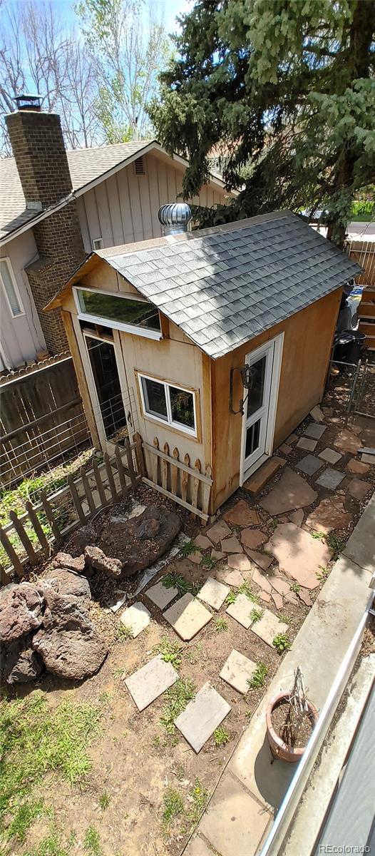 exterior space featuring fence, a chimney, and roof with shingles