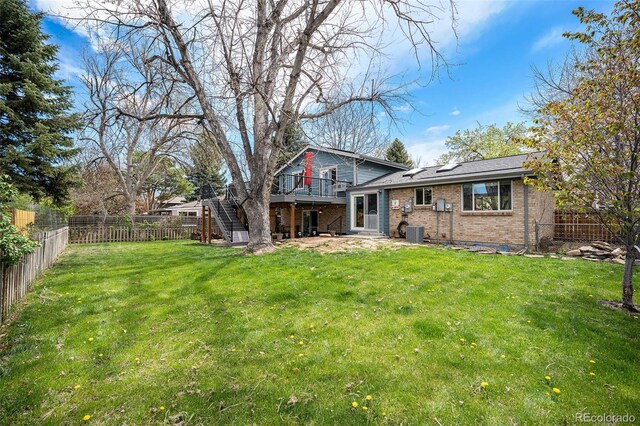 back of property featuring stairs, brick siding, a fenced backyard, central air condition unit, and a yard