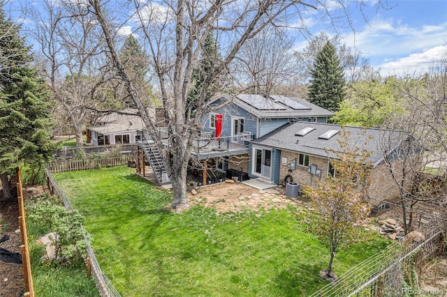 rear view of house featuring a deck, stairway, a fenced backyard, a yard, and a shingled roof