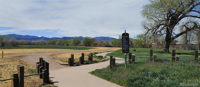 surrounding community with a mountain view and fence