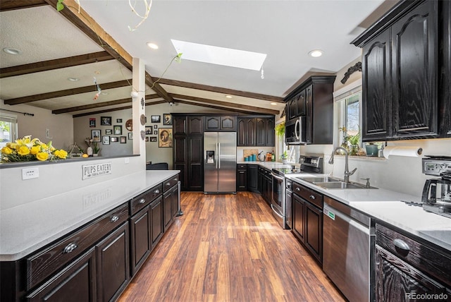 12175 W 68th Pl, Arvada, CO 80004 - kitchen featuring appliances with stainless steel finishes, a sink, a skylight, wood finished floors, and light countertops