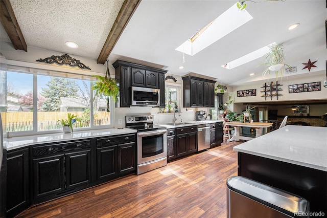12175 W 68th Pl, Arvada, CO 80004 - kitchen featuring appliances with stainless steel finishes, a skylight, a sink, dark cabinetry, and recessed lighting