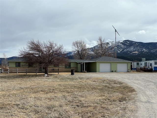 ranch-style home with a mountain view, a carport, driveway, and fence