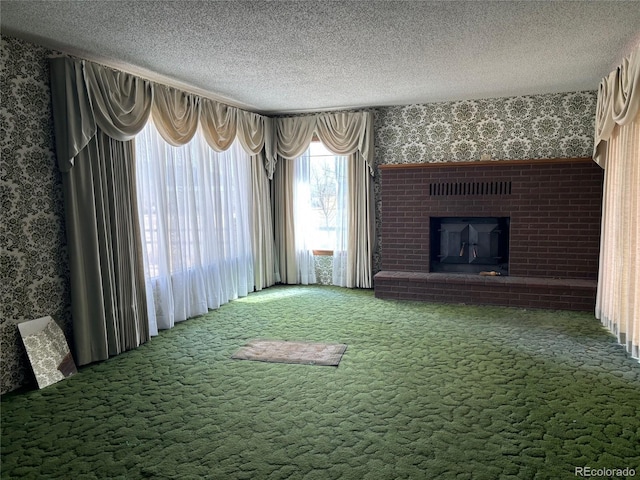 unfurnished living room featuring a textured ceiling, wallpapered walls, a fireplace, and carpet floors