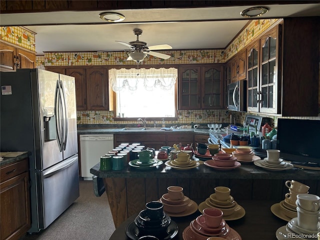 kitchen featuring glass insert cabinets, ceiling fan, decorative backsplash, appliances with stainless steel finishes, and a sink