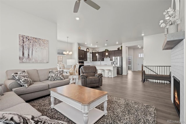 living room featuring dark wood-type flooring and ceiling fan with notable chandelier