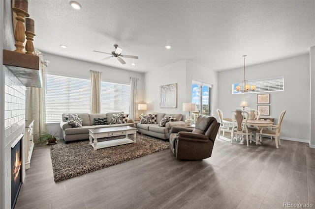 living room featuring ceiling fan with notable chandelier, dark hardwood / wood-style floors, and a textured ceiling