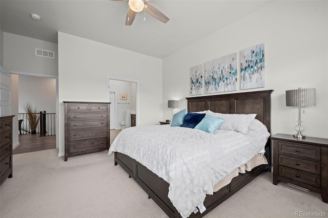 carpeted bedroom with ensuite bathroom and ceiling fan