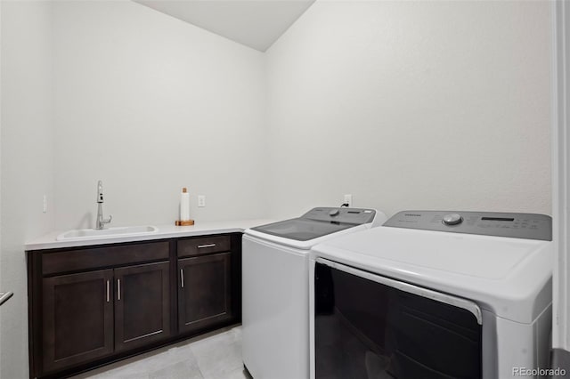 clothes washing area featuring cabinets, sink, and washing machine and clothes dryer