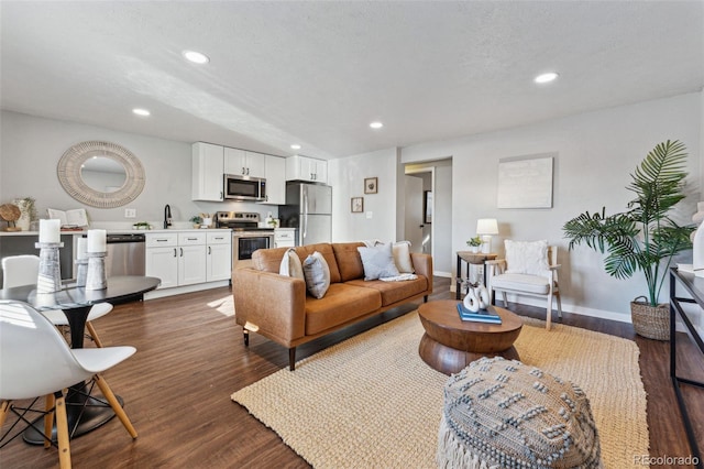 living room with a textured ceiling, sink, and dark wood-type flooring