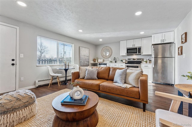 living room featuring hardwood / wood-style flooring, sink, a textured ceiling, and a baseboard heating unit