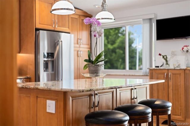 11131 Seton Pl, Westminster, CO 80031 - kitchen with stainless steel fridge, light stone countertops, brown cabinets, and pendant lighting