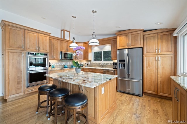 11131 Seton Pl, Westminster, CO 80031 - kitchen featuring appliances with stainless steel finishes, light wood finished floors, light stone counters, brown cabinets, and recessed lighting