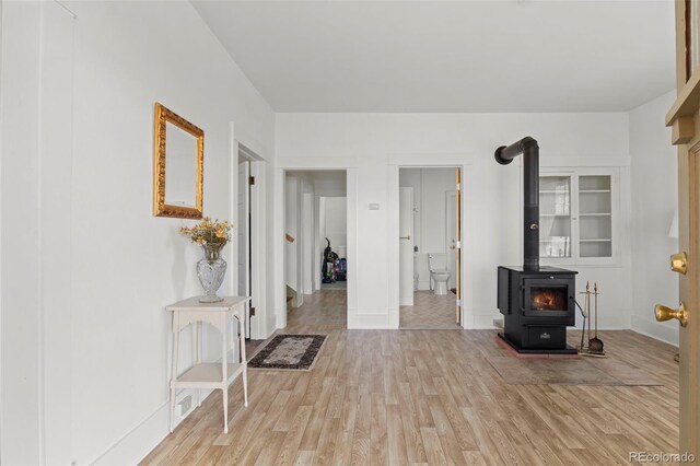 living room featuring light wood-style flooring, baseboards, and a wood stove