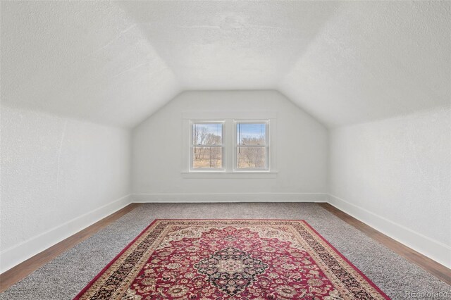 bonus room with wood finished floors, baseboards, vaulted ceiling, and a textured ceiling