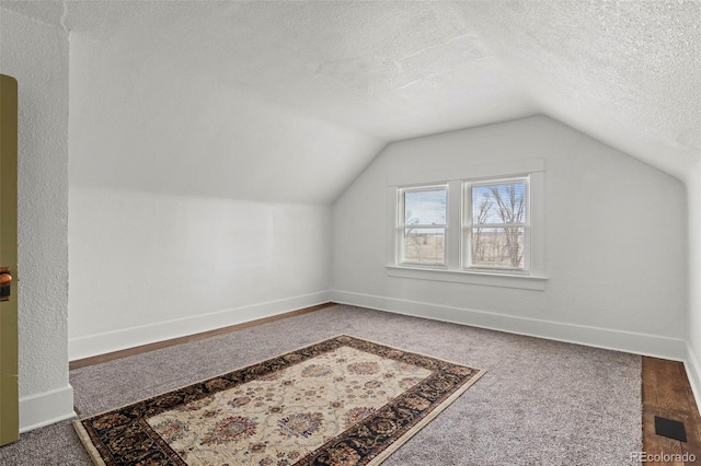 bonus room with baseboards, a textured ceiling, vaulted ceiling, and carpet