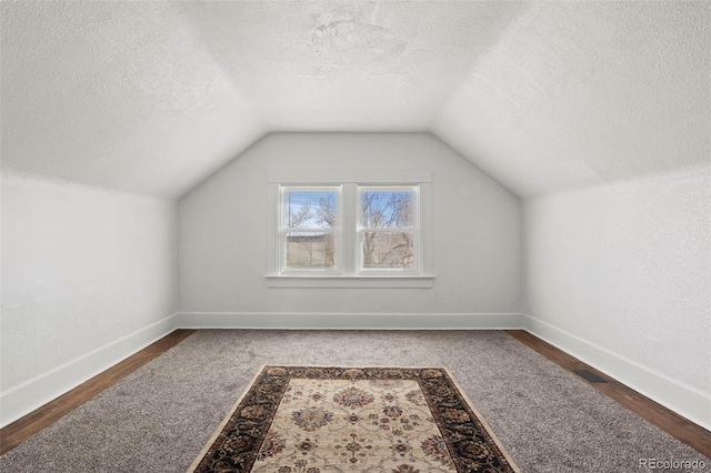 bonus room featuring baseboards, a textured ceiling, and vaulted ceiling