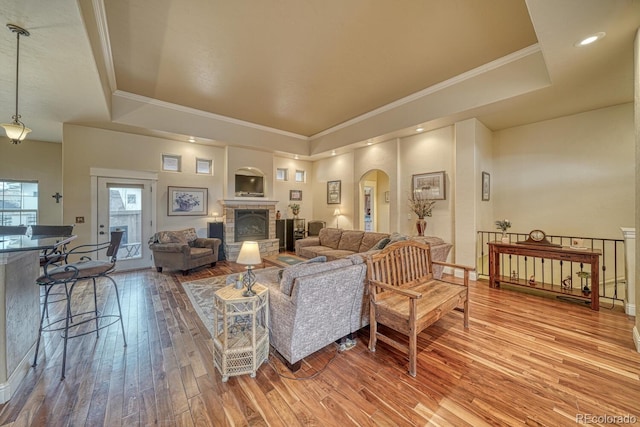 living room featuring a fireplace, hardwood / wood-style flooring, a raised ceiling, and ornamental molding