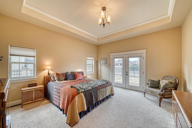 bedroom featuring access to exterior, french doors, an inviting chandelier, and a raised ceiling