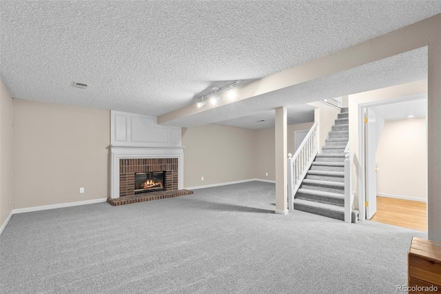 12665 Grove Ct, Broomfield, CO 80020 - unfurnished living room featuring stairway, a brick fireplace, carpet flooring, a textured ceiling, and track lighting