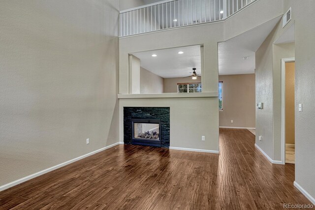 2452 S Andes Cir, Aurora, CO 80013 - unfurnished living room with wood finished floors, a ceiling fan, a fireplace, and a high ceiling