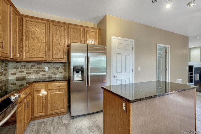 2452 S Andes Cir, Aurora, CO 80013 - kitchen featuring appliances with stainless steel finishes, dark stone counters, decorative backsplash, and brown cabinetry