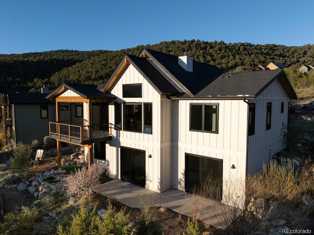 103 Paintbrush Way, Glenwood Springs, CO 81601 - view of front of home featuring a chimney, an attached garage, board and batten siding, a wooded view, and a wooden deck