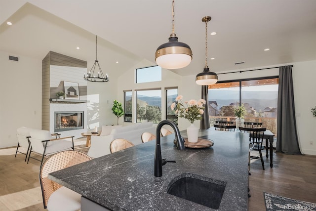 103 Paintbrush Way, Glenwood Springs, CO 81601 - kitchen with wood finished floors, vaulted ceiling, a fireplace, a chandelier, and decorative light fixtures