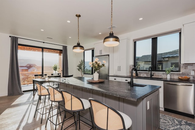 103 Paintbrush Way, Glenwood Springs, CO 81601 - kitchen with appliances with stainless steel finishes, a kitchen island with sink, wood finished floors, white cabinets, and backsplash