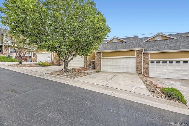 6727 W Yale Ave, Lakewood, CO 80227 - view of front of house featuring concrete driveway, a shingled roof, stone siding, and a garage
