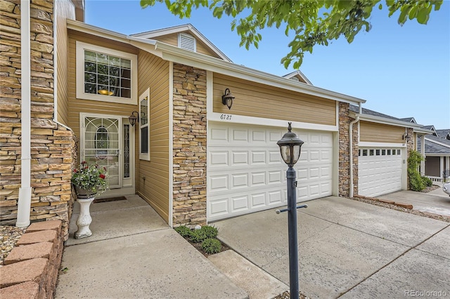 6727 W Yale Ave, Lakewood, CO 80227 - property entrance with stone siding, driveway, and a garage