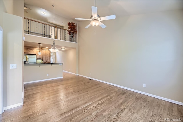 6727 W Yale Ave, Lakewood, CO 80227 - unfurnished living room featuring ceiling fan, light wood-style flooring, baseboards, and a high ceiling