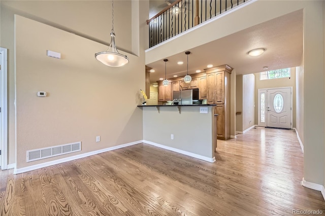 6727 W Yale Ave, Lakewood, CO 80227 - kitchen featuring a peninsula, dark countertops, freestanding refrigerator, light wood-style floors, and a kitchen breakfast bar