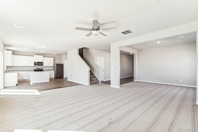974 Cascade Falls St, Severance, CO 80550 - unfurnished living room with light colored carpet, a ceiling fan, stairway, and recessed lighting