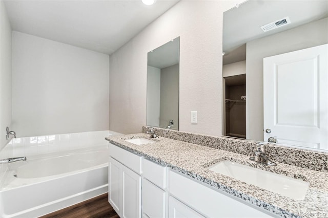974 Cascade Falls St, Severance, CO 80550 - full bathroom with double vanity, a bath, wood finished floors, and a walk in closet