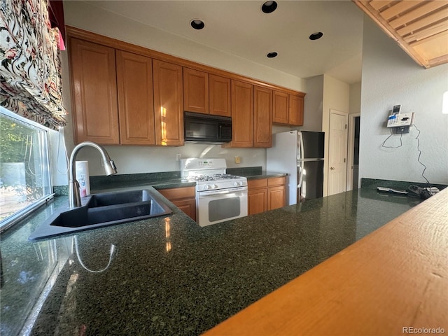 kitchen with sink, stainless steel fridge, and white gas range