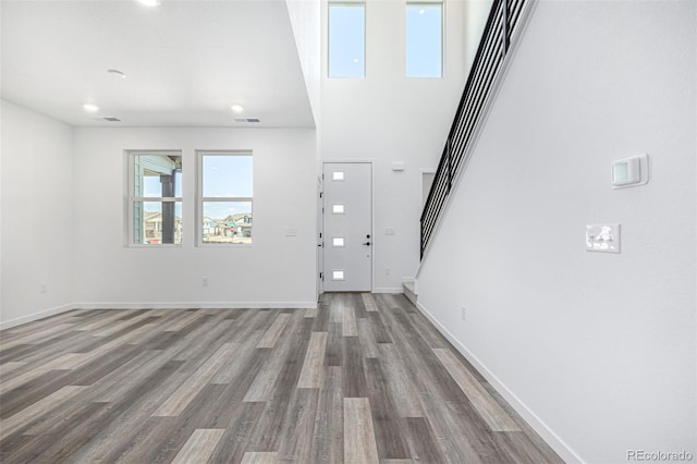 unfurnished living room with stairway, baseboards, visible vents, and wood finished floors