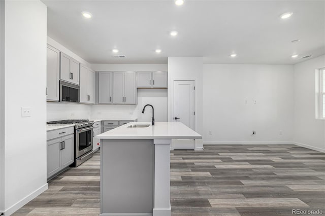 kitchen featuring recessed lighting, a sink, stainless steel appliances, a kitchen island with sink, and gray cabinets