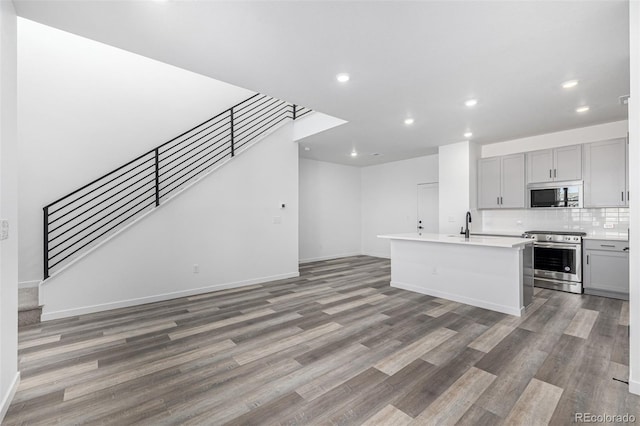 kitchen with light countertops, wood finished floors, stainless steel appliances, gray cabinetry, and recessed lighting
