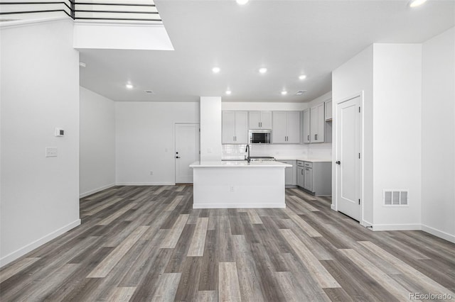 kitchen featuring wood finished floors, gray cabinets, stainless steel microwave, visible vents, and recessed lighting