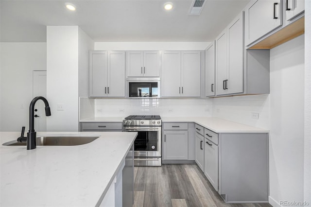 kitchen with a sink, visible vents, gray cabinetry, appliances with stainless steel finishes, and tasteful backsplash