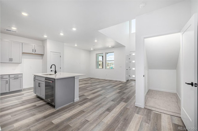 kitchen with a sink, light wood-type flooring, gray cabinets, dishwasher, and recessed lighting