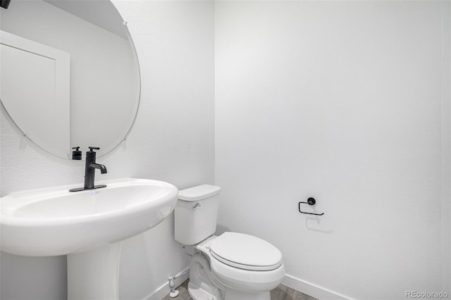 half bathroom featuring toilet and baseboards