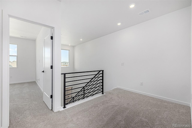 carpeted spare room with baseboards, a healthy amount of sunlight, and visible vents