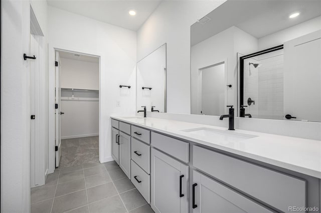 full bath featuring double vanity, a tile shower, a sink, a walk in closet, and recessed lighting