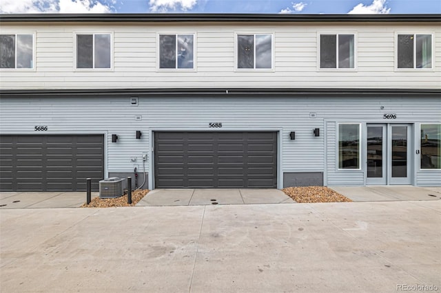 rear view of house featuring central AC unit, concrete driveway, and an attached garage