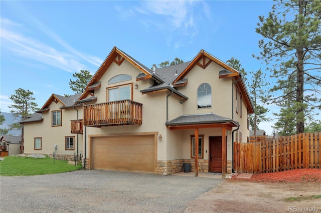 view of front of home with stone siding, stucco siding, driveway, and fence