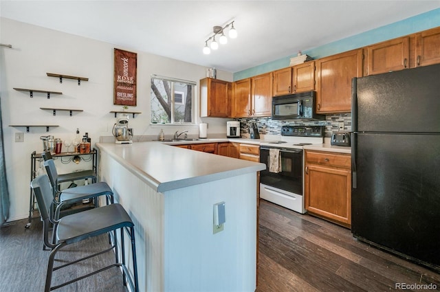 3831 Smoke Tree Dr, Colorado Springs, CO 80920 - kitchen with dark wood finished floors, a sink, black appliances, a peninsula, and a breakfast bar