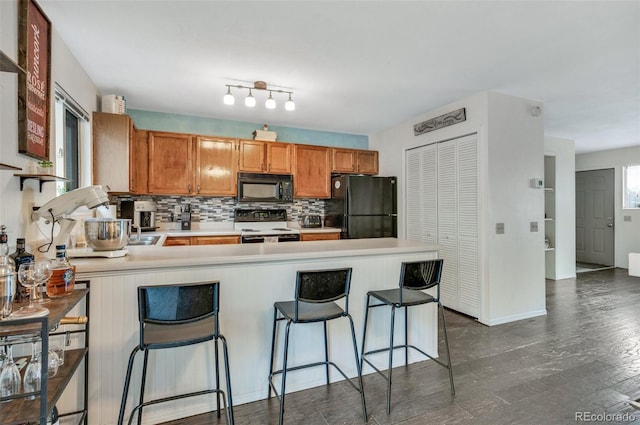 3831 Smoke Tree Dr, Colorado Springs, CO 80920 - kitchen featuring light countertops, a peninsula, decorative backsplash, dark wood-style floors, and black appliances