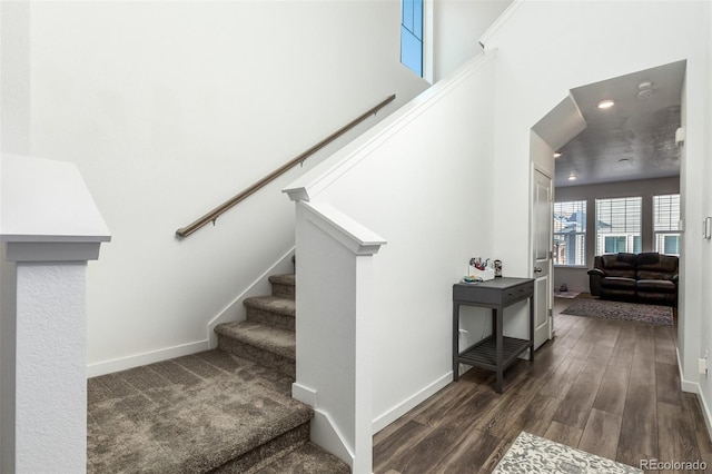 staircase with a towering ceiling, recessed lighting, baseboards, and wood finished floors